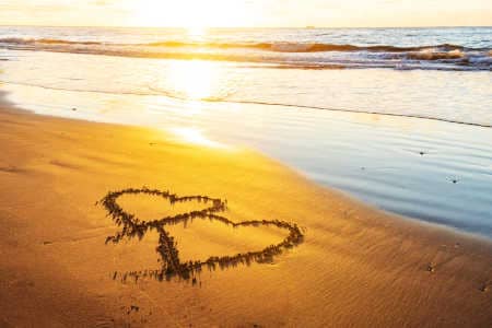 Menschen forman zwei Herzen am Strand Herzchakra heilen